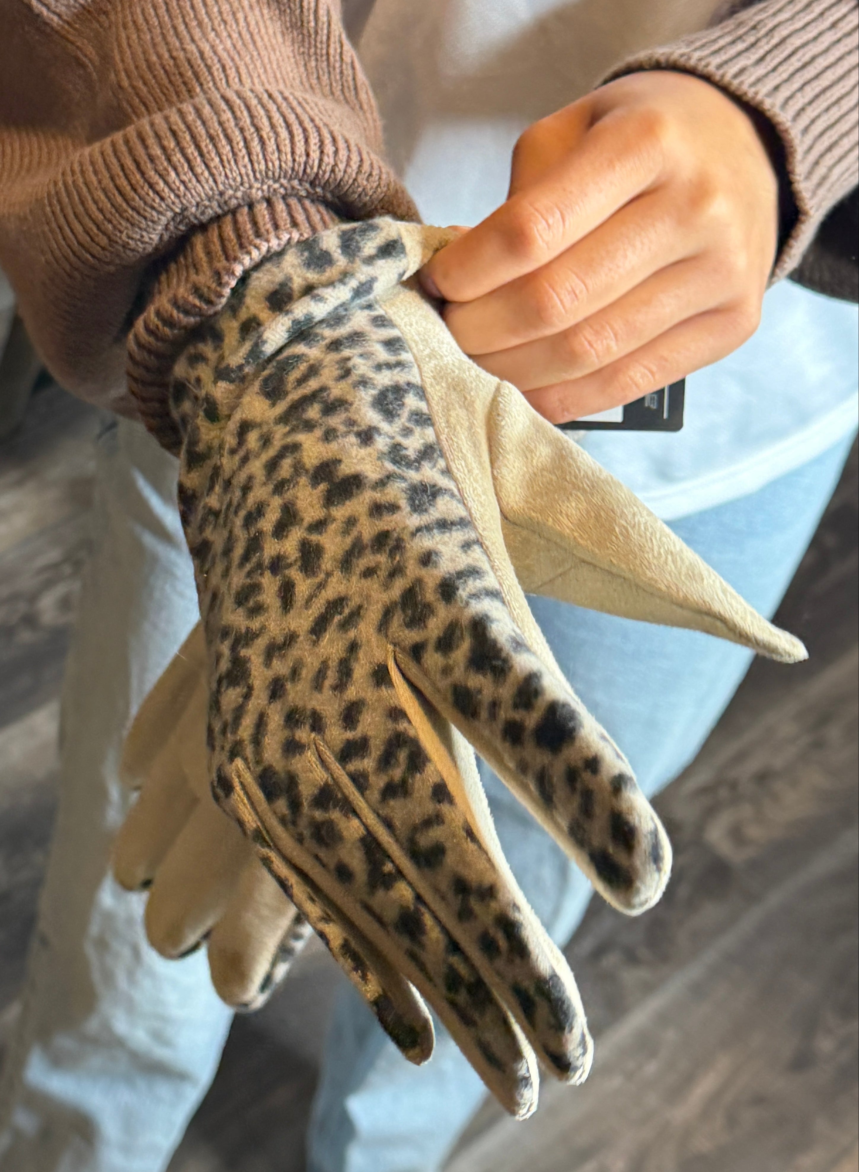 Person wearing a leopard print glove on a wooden floor