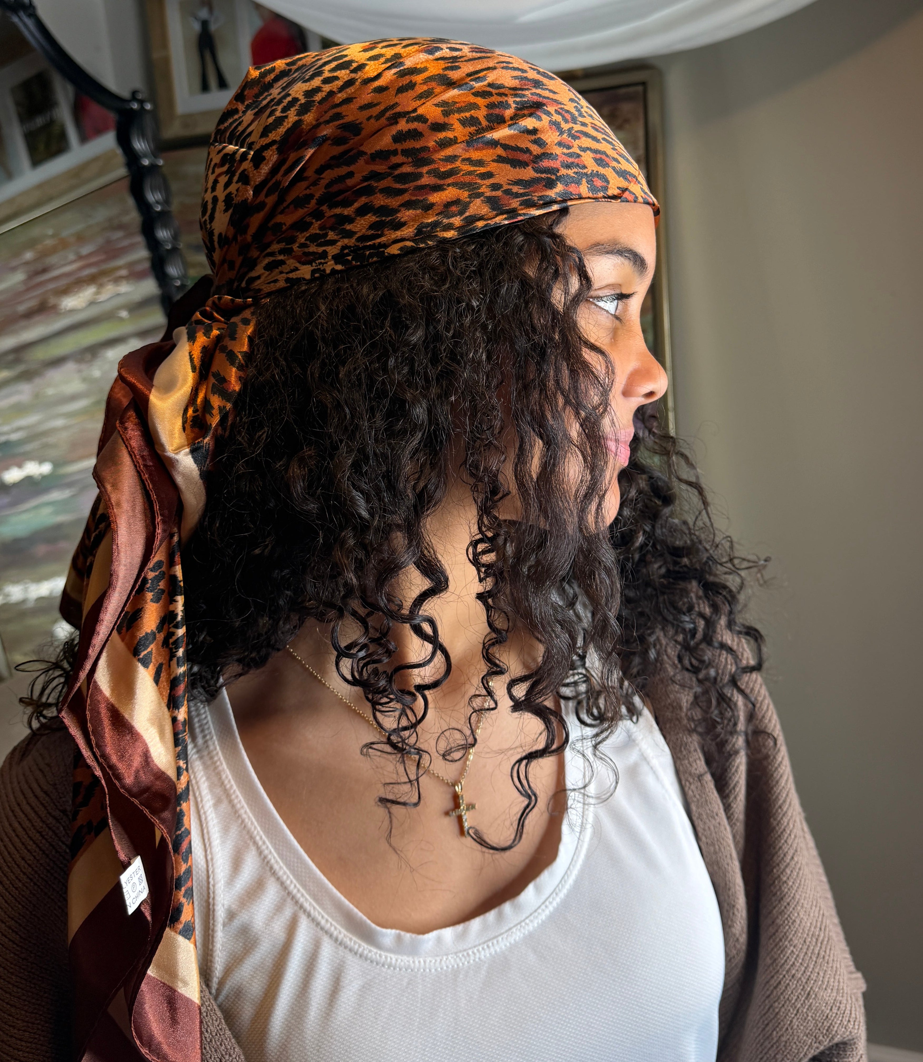 Person with leopard print headscarf and tattoos on neck and chest in a casual setting.