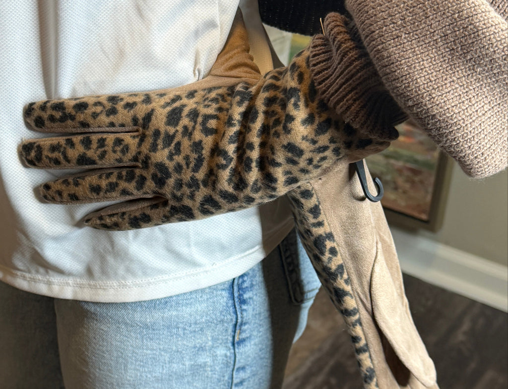 Person wearing a leopard print glove on a white surface with a blurred background