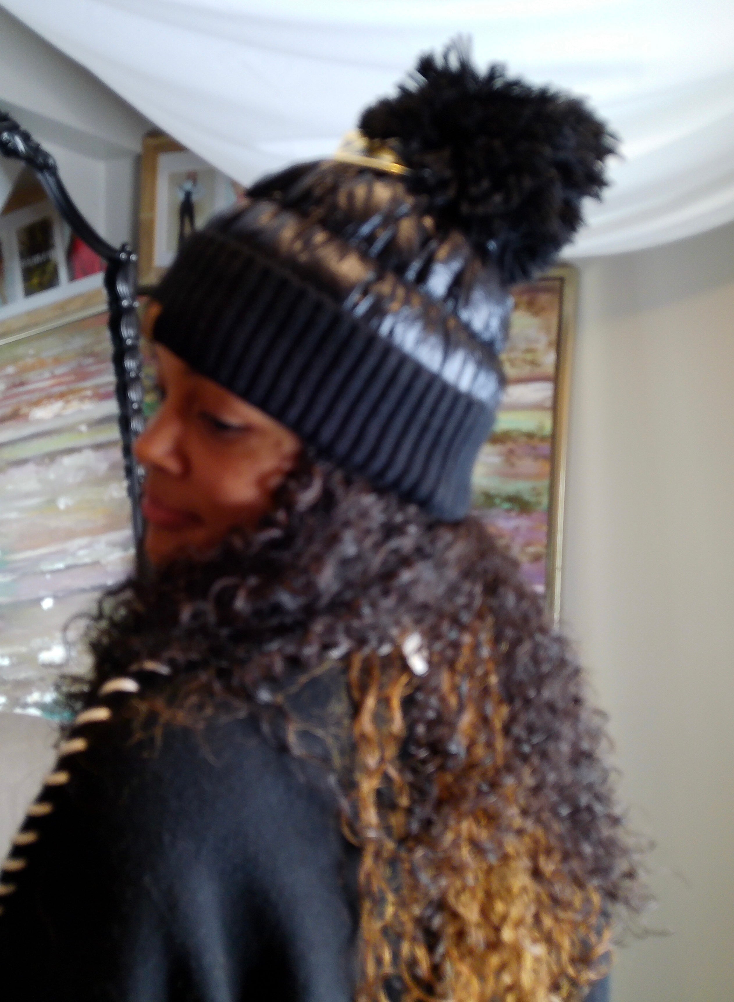 Person wearing a black knit beanie with a pom-pom indoors