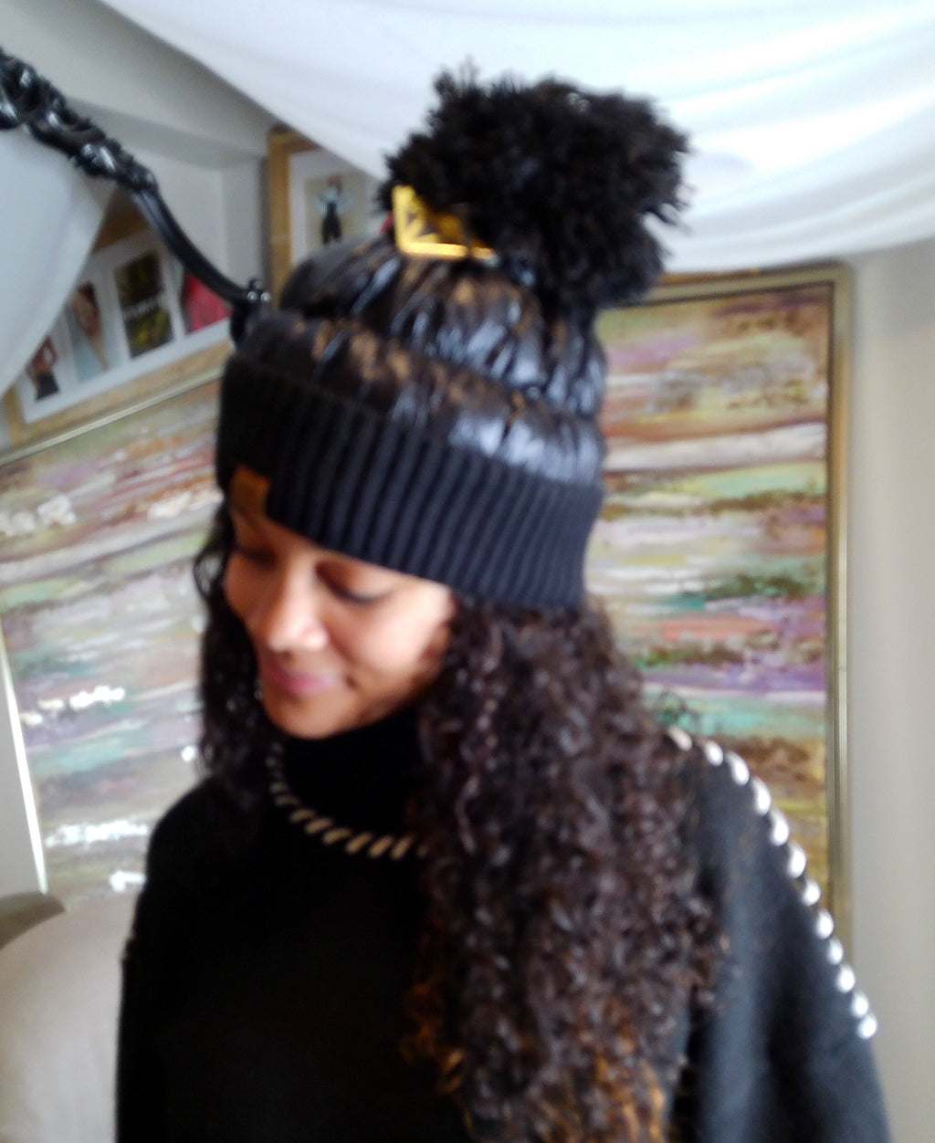 Person wearing a black knit hat with pom-poms indoors