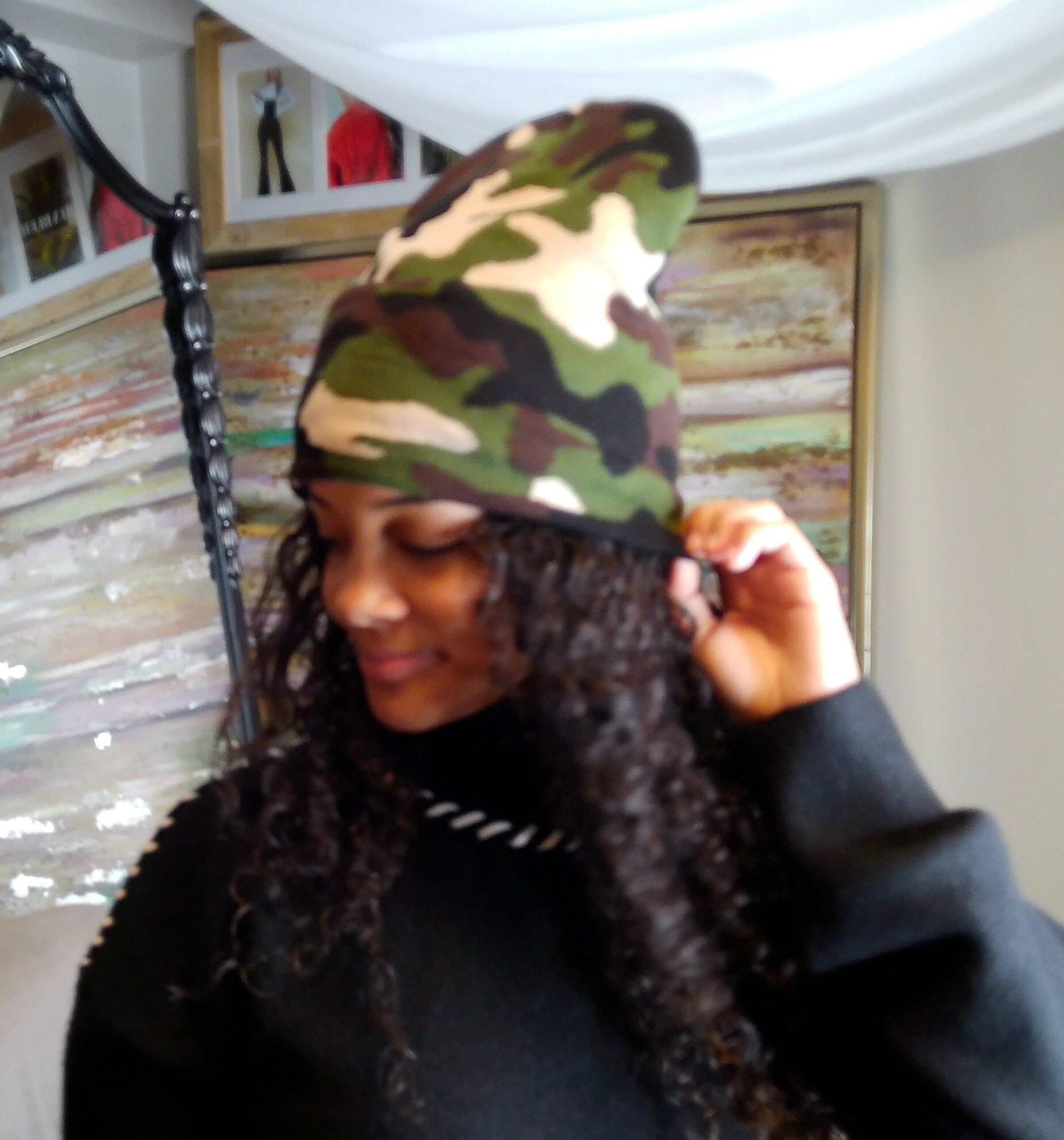 Person wearing a camouflage beanie indoors with a decorative wall in the background