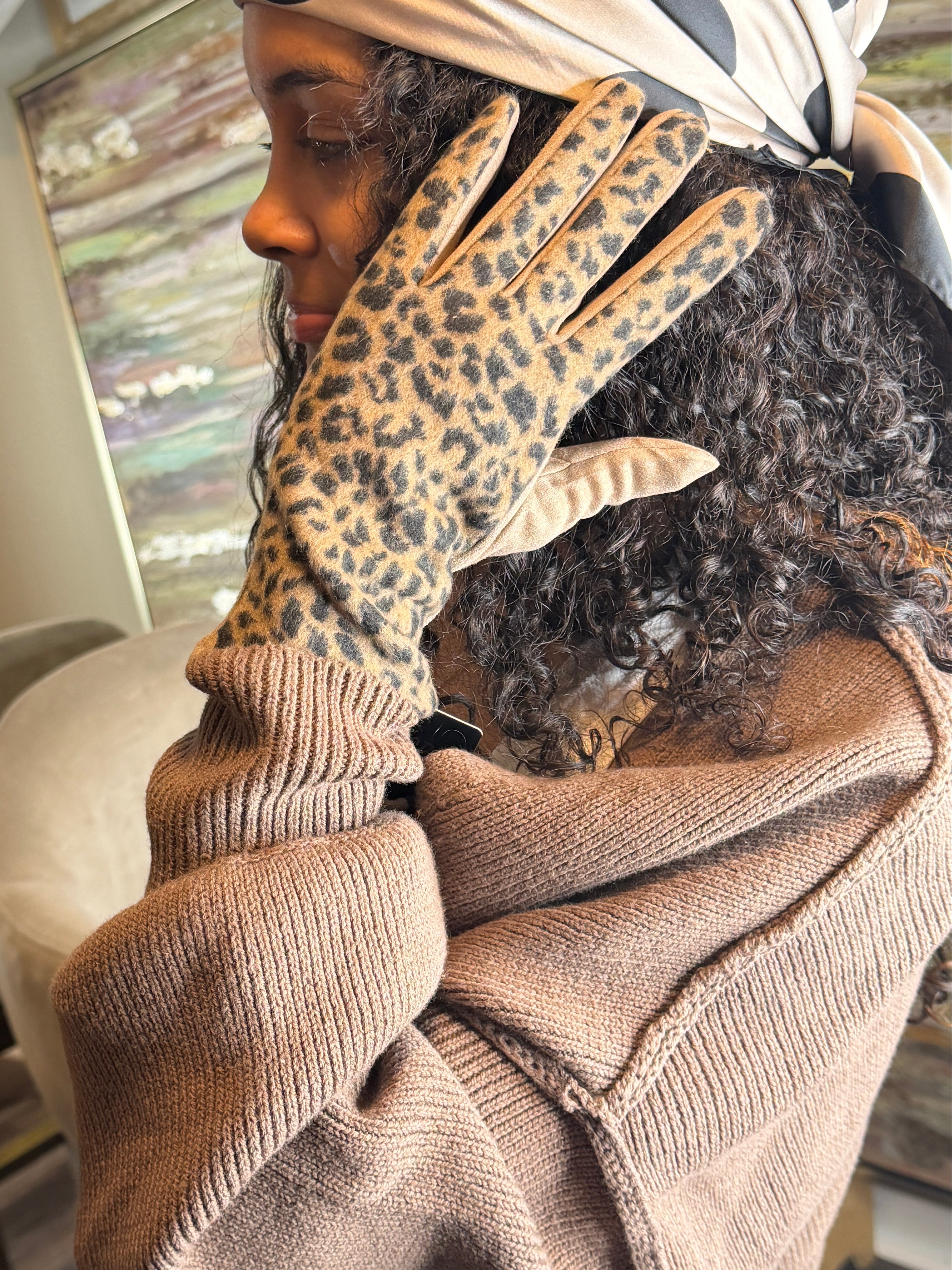 Person wearing a leopard print glove and beige sweater indoors