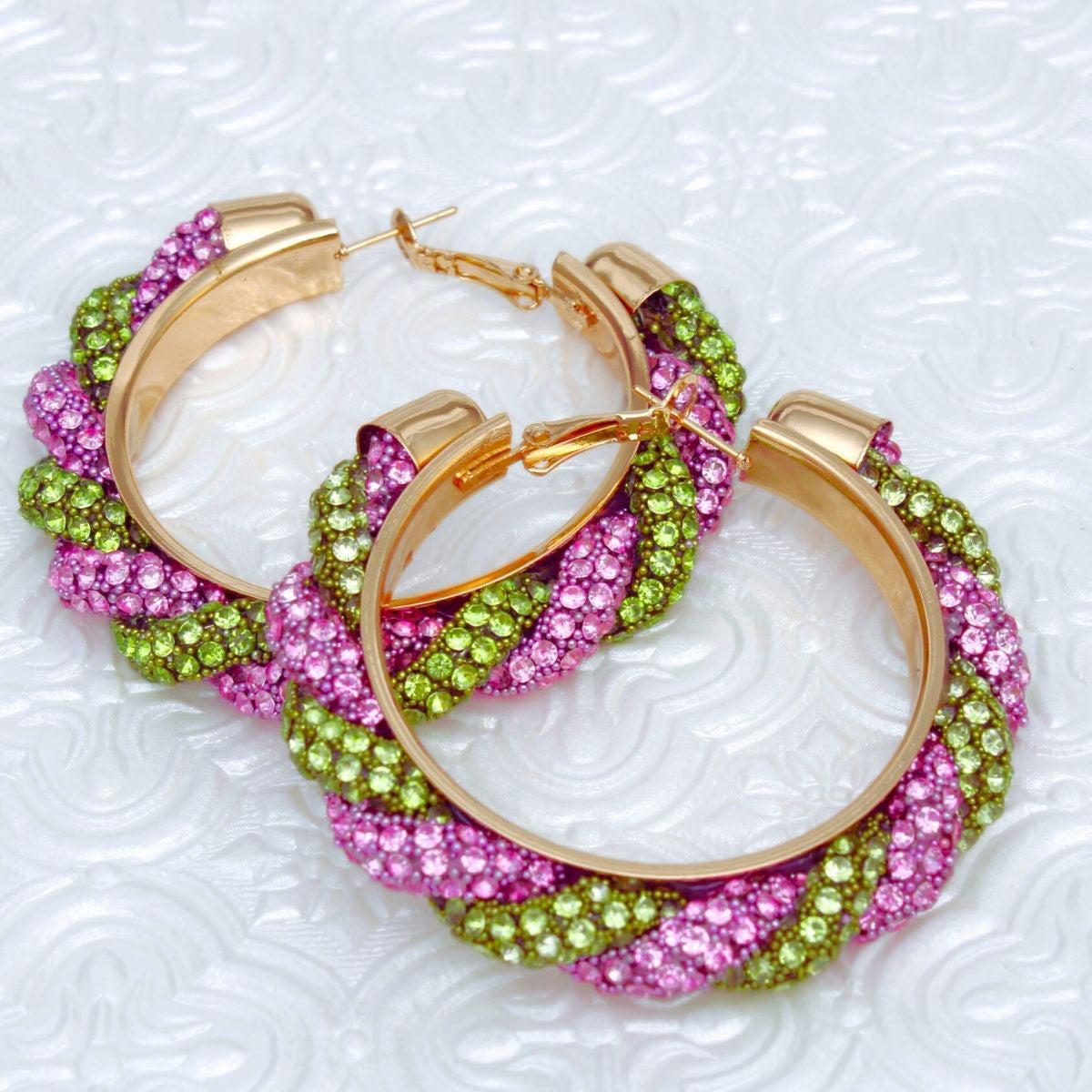 Pink green twisted tube hoop earrings worn on ear front view vibrant